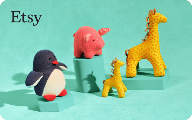 Still life photograph of plush toy animals on a teal background. On the left, a penguin with a white belly, black body and red feet. In the centre, a pink pig with darker pink details sits atop a teal block. To the right, two giraffes – one large with yellow fabric and orange spots, and a smaller one with lighter yellow and orange spots – stand near each other, with the smaller giraffe in front of a shorter teal block.